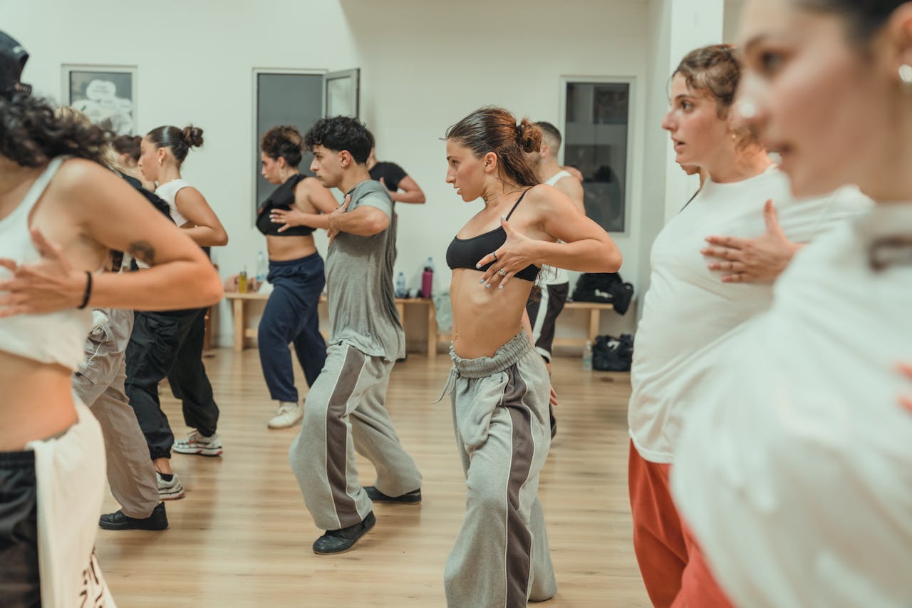 Energetic group dance class with adults performing choreography in a studio.