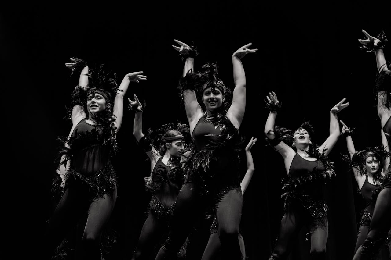 Captivating black and white photo of energetic dancers in costume on stage.