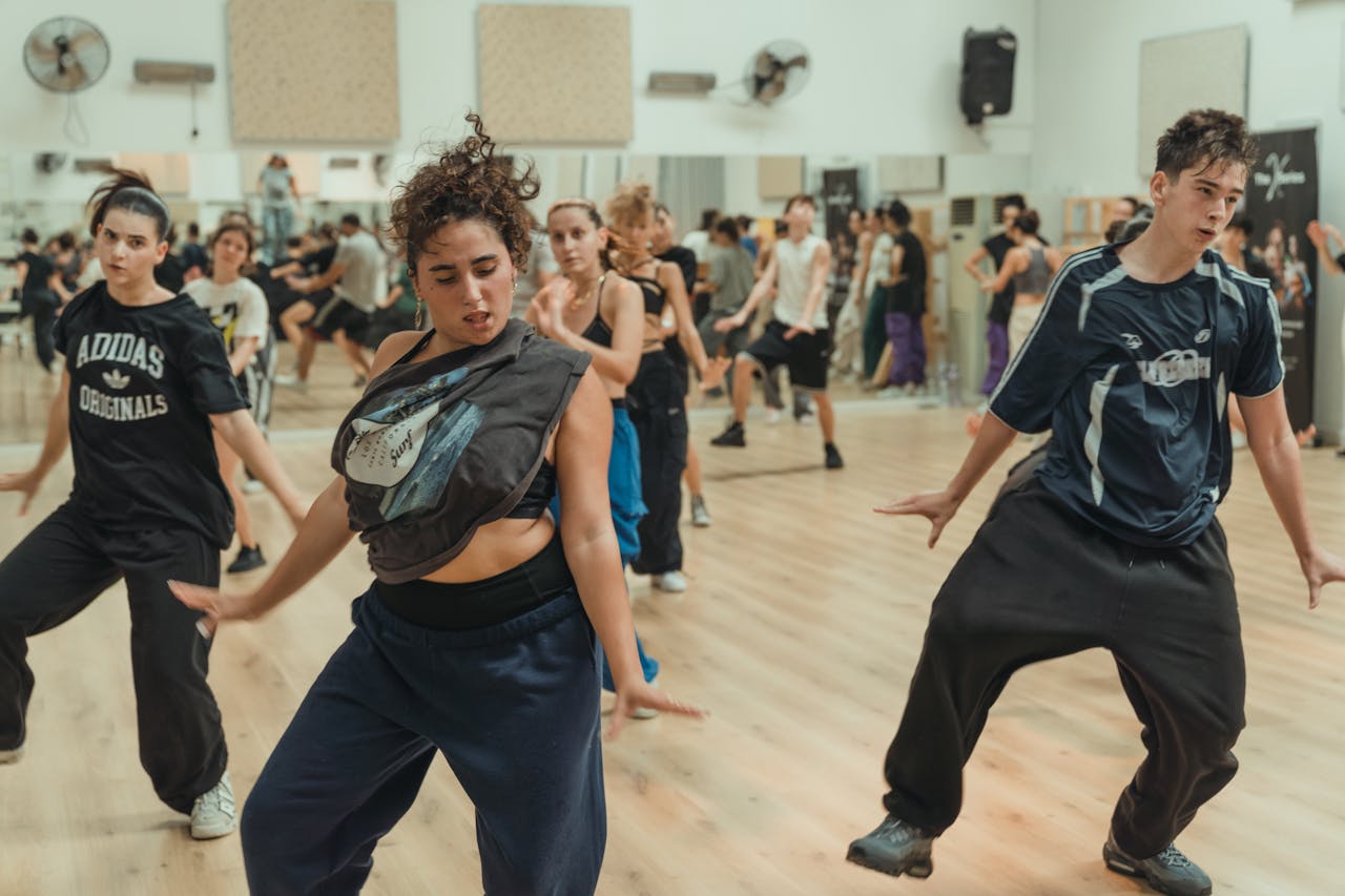 Energetic dance class with diverse teenagers showcasing street dance moves in a lively studio setting.